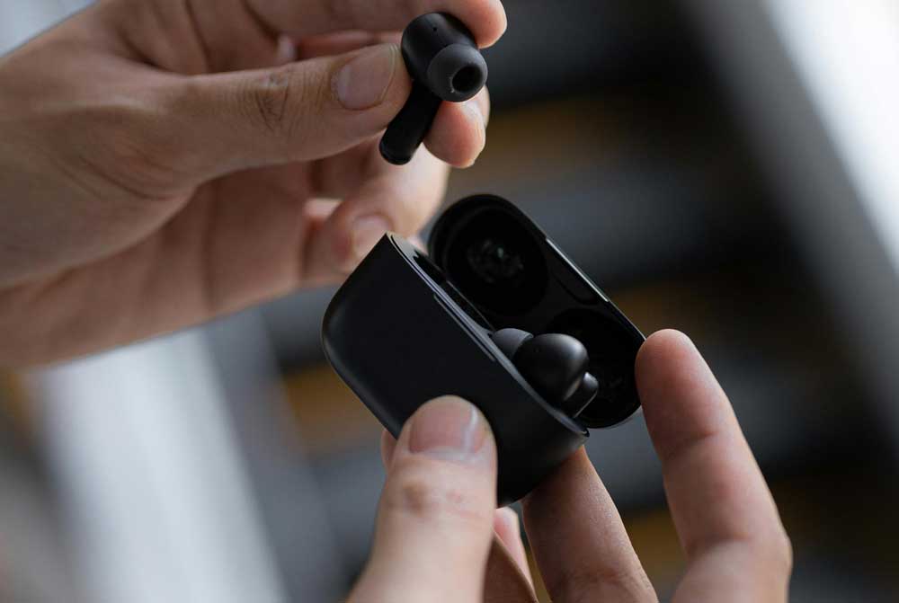 Person holding true wireless earbuds