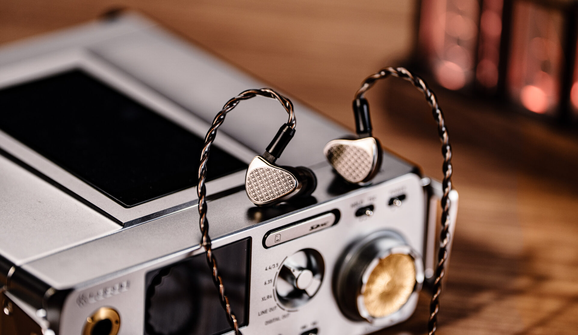 Pair of in-ear monitors resting on a portable audio player, illustrating high-resolution personal audio and hybrid IEM design.